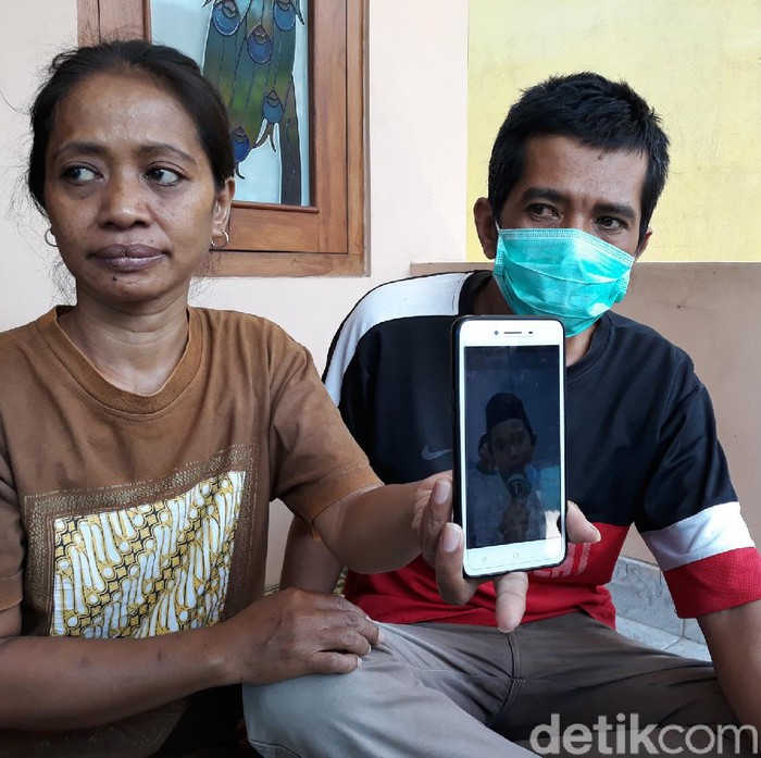 Driver ojol, Bandiman dan istrinya menunjukkan foto buah hatinya yang meninggal usai makan paket takjil misterius