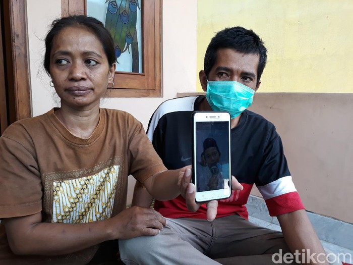 Driver ojol, Bandiman dan istrinya menunjukkan foto buah hatinya yang meninggal usai makan paket takjil misterius