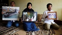 Keluarga memegang foto Kolonel Laut (P) Harry Setiawan di rumah mereka di Depok, 24 April lalu. Rayi Gigih/AFP.