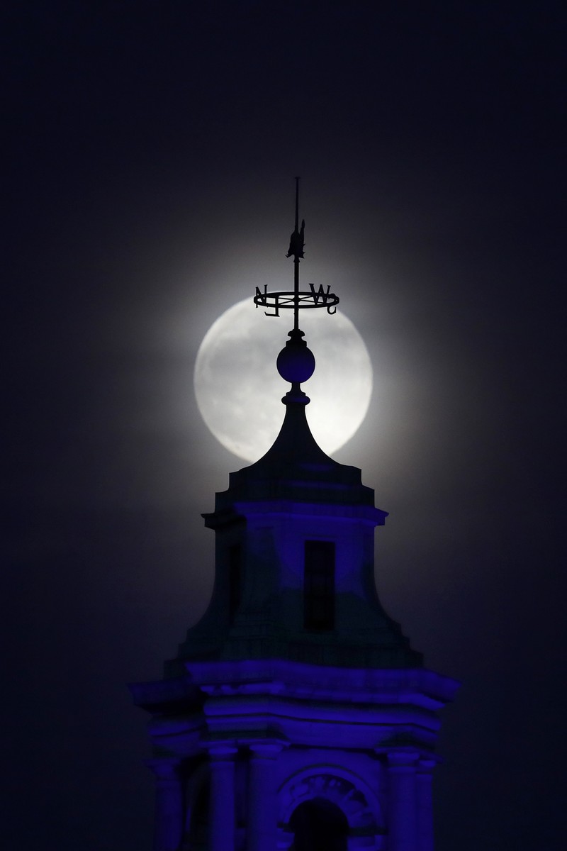 The moon rises through cloud over County Hall in London, Monday, April 26, 2021. This moon is a supermoon, meaning it appears larger than an average full moon because it nearer the closest point of its orbit to Earth. (AP Photo/Kirsty Wigglesworth)