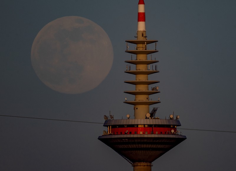 The full moon rises behind the television tower in Frankfurt, Germany, Monday, April 26, 2021. (AP Photo/Michael Probst)