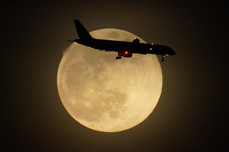 A jet is silhouetted by the rising moon as it approaches Louisville International Airport, Monday, April 26, 2021, in Louisville, Ky. This moon is a supermoon, meaning it appears larger than an average full moon because it is nearer the closest point of its orbit to Earth. (AP Photo/Charlie Riedel)
