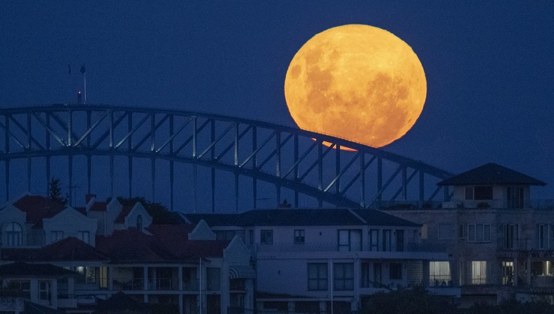 The moon rises over the Sydney Harbour Bridge in Australia, Tuesday, April 27, 2021. This moon is a supermoon, meaning it appears larger than an average full moon because it is nearer the closest point of its orbit to Earth. (AP Photo/Mark Baker)