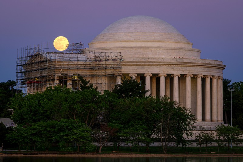 The moon rises over the scaffolding surrounding the entrance to the Jefferson Memorial, in Washington, late Monday, April, 26, 2021. The Jefferson Memorial is in the middle of a multi-year renovation project. (AP Photo/J. David Ake)