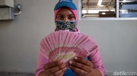 Seorang buruh menunjukan uang THR-nya.