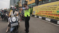 Polisi mengarahkan pengendara motor untuk melewati jalur yang benar saat simulasi penyekatan larangan mudik di Bundaran Waru, Surabaya, Jawa Timur, Kamis (29/4/2021). ANTARA FOTO/Didik Suhartono