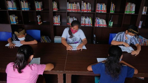 Siswa belajar secara daring dengan memanfaatkan fasilitas wifi gratis di perpustakaan desa.