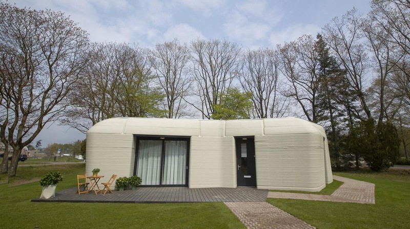 View of the living room with the open kitchen showing the printer layers in the walls of the 3D-printed 94-square meters (1,011-square feet) two-bedroom bungalow resembling a boulder with windows in Eindhoven, Netherlands, Friday, April 30, 2021. The fluid, curving lines of its gray walls look natural. But they are actually at the cutting edge of housing construction in the Netherlands and around the world. They were 3D printed at a nearby factory. (AP Photo/Peter Dejong)