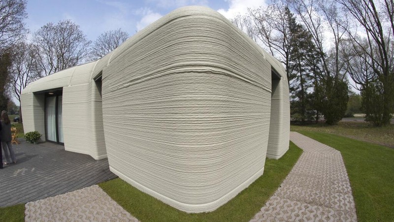 View of the living room with the open kitchen showing the printer layers in the walls of the 3D-printed 94-square meters (1,011-square feet) two-bedroom bungalow resembling a boulder with windows in Eindhoven, Netherlands, Friday, April 30, 2021. The fluid, curving lines of its gray walls look natural. But they are actually at the cutting edge of housing construction in the Netherlands and around the world. They were 3D printed at a nearby factory. (AP Photo/Peter Dejong)