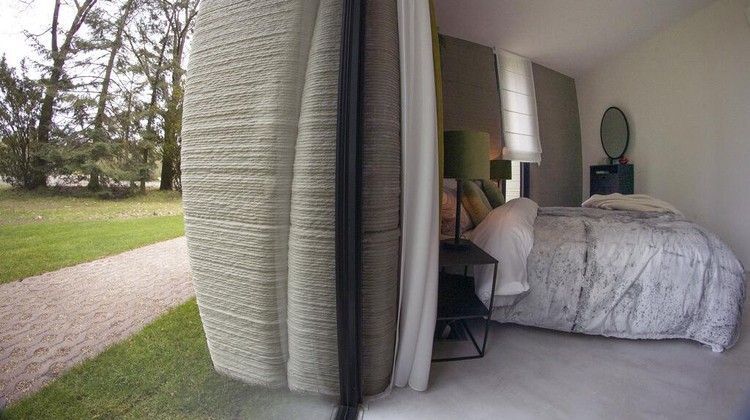 View of the living room with the open kitchen showing the printer layers in the walls of the 3D-printed 94-square meters (1,011-square feet) two-bedroom bungalow resembling a boulder with windows in Eindhoven, Netherlands, Friday, April 30, 2021. The fluid, curving lines of its gray walls look natural. But they are actually at the cutting edge of housing construction in the Netherlands and around the world. They were 3D printed at a nearby factory. (AP Photo/Peter Dejong)