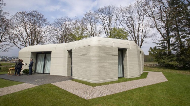 View of the living room with the open kitchen showing the printer layers in the walls of the 3D-printed 94-square meters (1,011-square feet) two-bedroom bungalow resembling a boulder with windows in Eindhoven, Netherlands, Friday, April 30, 2021. The fluid, curving lines of its gray walls look natural. But they are actually at the cutting edge of housing construction in the Netherlands and around the world. They were 3D printed at a nearby factory. (AP Photo/Peter Dejong)