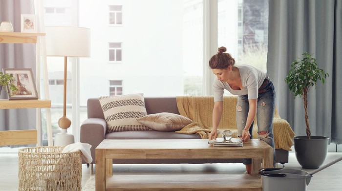 Shot of a young woman cleaning her living room