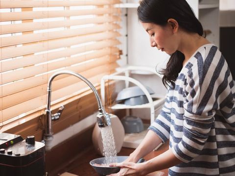Asian maid housewife washing cleaning dishes in kitchen