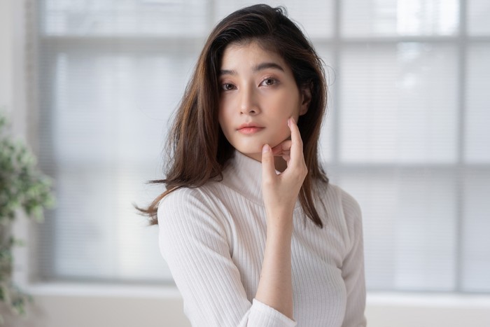 Asian woman is applying cream to her face.