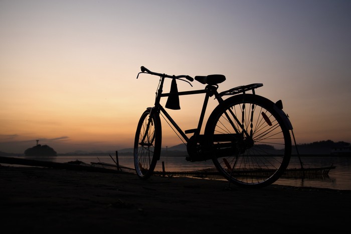 Ilustrasi sepeda A bicycle in the banks of Brahmaputra river at sunset