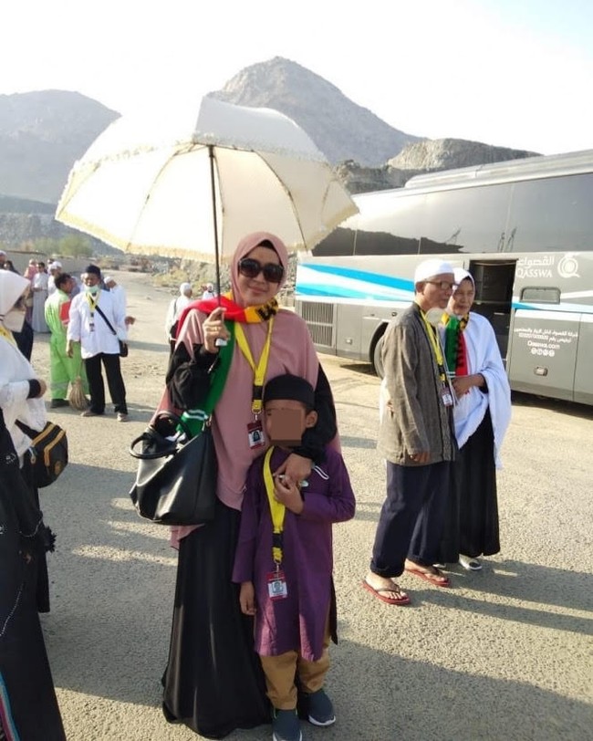 Ketika beribadah ke Tanah Suci, Mellya Juniarti memakai gamis hitam dipadukan dengan bergo instan yang berukuran jumbo warna pastel pink. Bergo tersebut bisa menutupi bagian depan dan belakang. Foto: Dok. Instagram @mizyanhadziq.