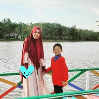 Hak asuh anak yang jatuh ke tangannya, Mellya Juniarti kerap mengajak sang buah hati liburan. Dalam foto ini, Mellya Juniarti megenakan khimar merah marun panjang dikombinasikan dengan gamis yang berwarna senada. Foto: Dok. Instagram @mizyanhadziq.