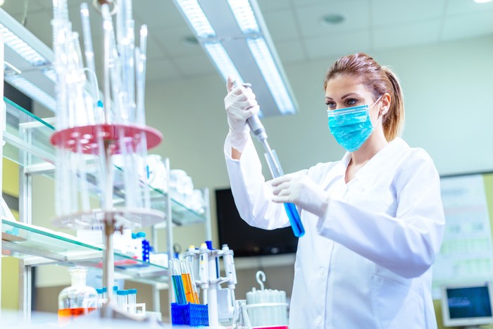 Woman in laboratory, examining new potions for the scientific research at university. Woman is wearing protective mask and protective gloves (Surgical gloves) while working with beakers, test tubes and other lab equipment. Series of images, taken with Nikon D800 and 50mm or 85 mm professional lens, developed from RAW.