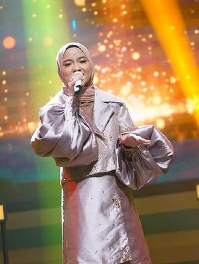 Penampilan kedua, gayanya lebih glamor berblazer metalik dengan aksen puff pada bagian lengan. Ia pun memadukan busananya dengan jilbab warna nude cokelat. Foto: Dok. InsertLive