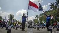 Mereka juga mengibarkan bendera merah putih dan organisasi buruh selama aksi di kawasan Patung Kuda.