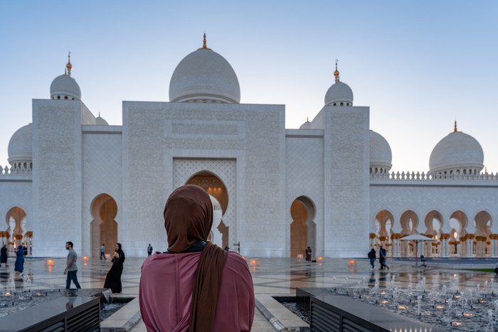 Woman in Hijab looking at a  mosque at sunset | Abu Dhabi Sheik Zayed Mosque | Beautiful islamic architecture | Tourist attraction
- Abu Dhabi, UAE, March 22, 2020