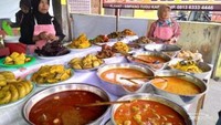 Uni penjual Nasi Kapau menunggu pembeli di hadapan hidangannya