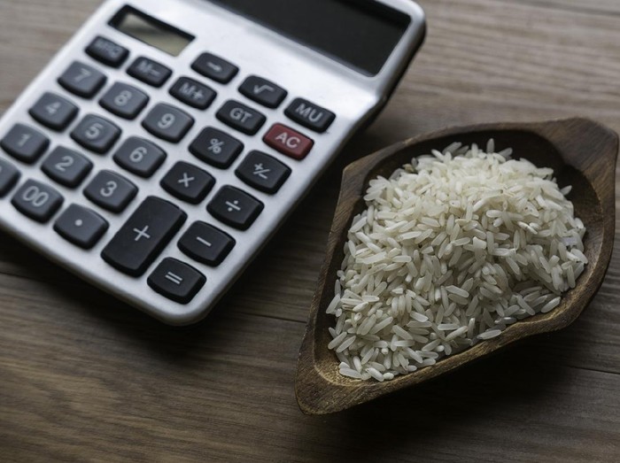 Selective focus of rice and calculator on wooden background.