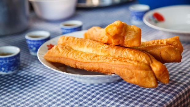 Youtiao (Chinese fried churro, Chinese cruller, Chinese oil stick, Chinese doughnut, fried breadstick), long golden brown deep fried dough strip, eaten at breakfast with rice congee, tea or sweet milk