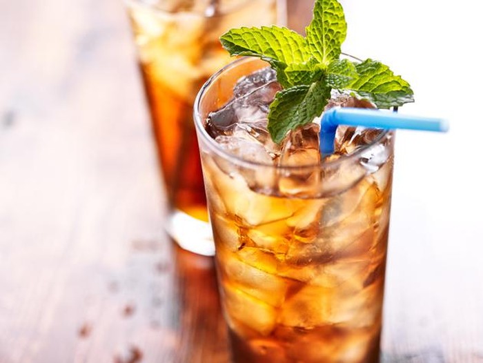 iced tea with blue straw and mint garnish , shot with selective focus.