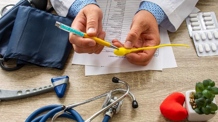 Doctor during consultation held in his hand and shows patient anatomical model of male sperm. Counseling of men and couples about male infertility, sperm pathology, impossibility to get pregnant