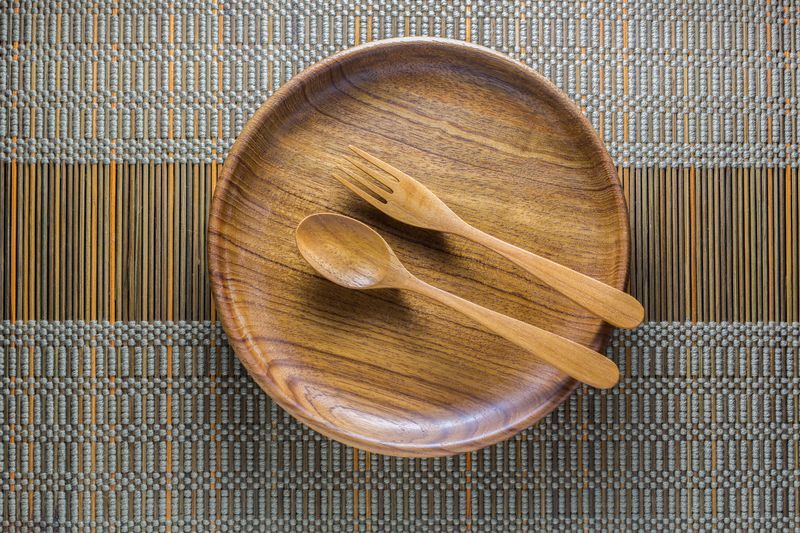 Dinning utensil set up on a green weaved bamboo mat