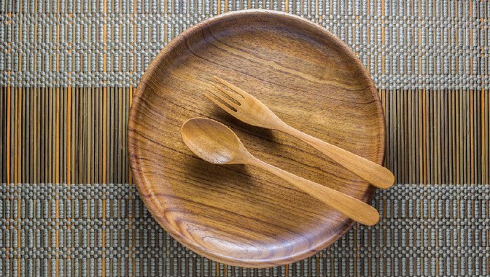Piring dan sendok kayu Dinning utensil set up on a green weaved bamboo mat