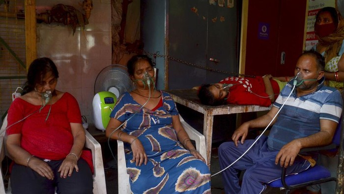 FILE - In this April 30, 2021, file photo, health workers attend to COVID-19 patients at a makeshift hospital in New Delhi, India. COVID-19 infections and deaths are mounting with alarming speed in India with no end in sight to the crisis. People are dying because of shortages of bottled oxygen and hospital beds or because they couldn’t get a COVID-19 test. (AP Photo/File)