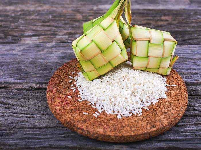 Ketupat (Rice Dumpling) and rice On Wood Background. Ketupat is a natural rice casing made from young coconut leaves for cooking rice during eid Mubarak