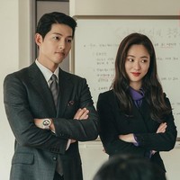 Office look ala Jeon Yeo Bin tak sebatas setelan jas dan celana. Ia juga mengenakan gaun berwarna hitam yang selintas menyerupai coat. Potongan gaun ini mempertegas lekukan tubuh, dengan detail renda di bagian ujung lengan. Foto: dok. tvN