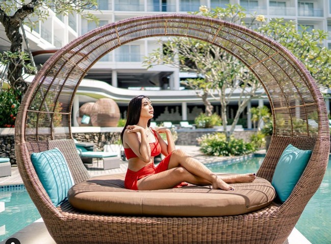 Seperti penampilannya dalam foto ini. Berpose di tepi kolam, Millen menggunakan atasan crop top merah dengan rok mini warna senada.  Foto: dok. Instagram/@millencyrus