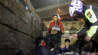Ada beberapa orang yang menumpang di atas bak truk tersebut. Seorang polisi terlihat memeriksa salah seorang penumpan bak tersebut.