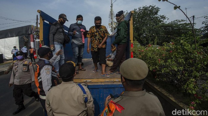 Petugas Satpol PP menurunkan penumpang truk di Kedungwaringin, Kabupaten Bekasi, Jumat (7/4/2021).