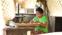 Salah seorang pengrain sedang menganyam bambu