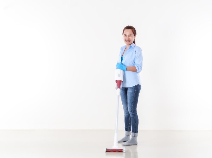 Beautiful asian woman in protective gloves and holding a vacuum cleaner for cleaning floor.