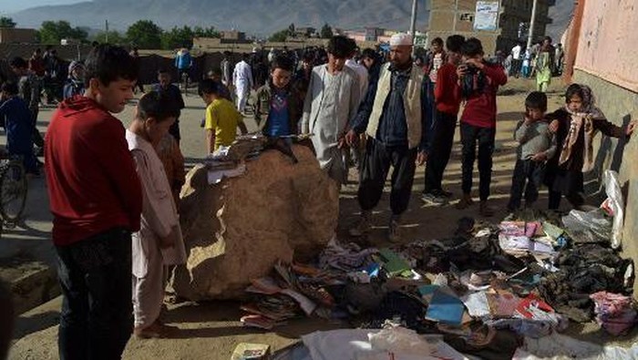 EDITORS NOTE: Graphic content / Onlookers stand next to a pile of backpacks and books of victims following multiple blasts outside a girls school in Dasht-e-Barchi on the outskirts of Kabul on May 9, 2021, as the death toll has risen to 50, the interior ministry said. (Photo by WAKIL KOHSAR / AFP)