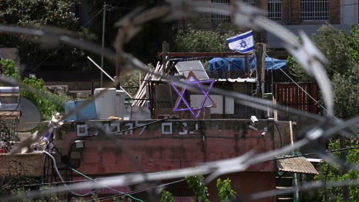 The Star of David and an Israeli flag are seen on top of a house in the Sheikh Jarrah neighbourhood of occupied east Jerusalem on May 5, 2021. - Israeli Jews backed by courts have taken over houses in Sheikh Jarrah in east Jerusalem on the grounds that Jewish families lived there before fleeing in Israels 1948 war for independence. The claimants seek to evict a total of 58 more Palestinians, according to the watchdog group Peace Now, and  Israels Supreme Court is set to announce a decision for four of those families on May 6, 2021. (Photo by Emmanuel DUNAND / AFP)