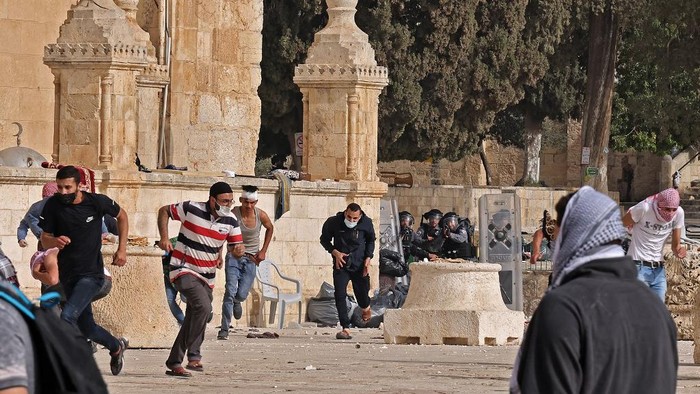 Palestinians run for cover amid clashes with Israeli security forces at Jerusalems Al-Aqsa mosque compound on May 10, 2021, ahead of a planned march to commemorate Israels takeover of Jerusalem in the 1967 Six-Day War. (Photo by ahmad gharabli / AFP)