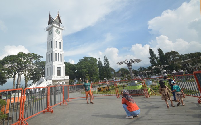 Pengunjung berfoto di pelataran Jam Gadang yang ditutup dengan pagar, di Bukittinggi, Sumatera Barat, Minggu (9/5/2021). Kapolda Sumbar Irjen Pol Toni Harmanto memastikan seluruh objek wisata di provinsi itu ditutup saat libur Idul Fitri 1442 hijriah untuk mencegah penyebaran virus COVID-19. ANTARA FOTO/Iggoy el Fitra/hp.