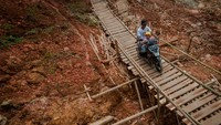 Warga mengendarai motor melintasi jembatan yang dibangun secara swadaya di Desa Citorek Kidul, Lebak, Banten, Senin (10/5/2021).   