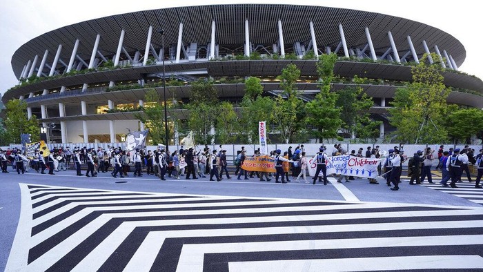 Takut Corona, Warga Jepang Demo Tolak Olimpiade Tokyo People who are against the Tokyo 2020 Olympics set to open in July, march around Tokyo's National Stadium, back, during an anti-Olympics demonstration Sunday, May 9, 2021. (AP Photo/Eugene Hoshiko)