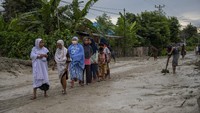 Sejumlah warga melintasi jalan yang tertutup lumpur di Desa Beka, Marawola, Kabupaten Sigi, Sulawesi Tengah, Selasa (11/5/2021).
