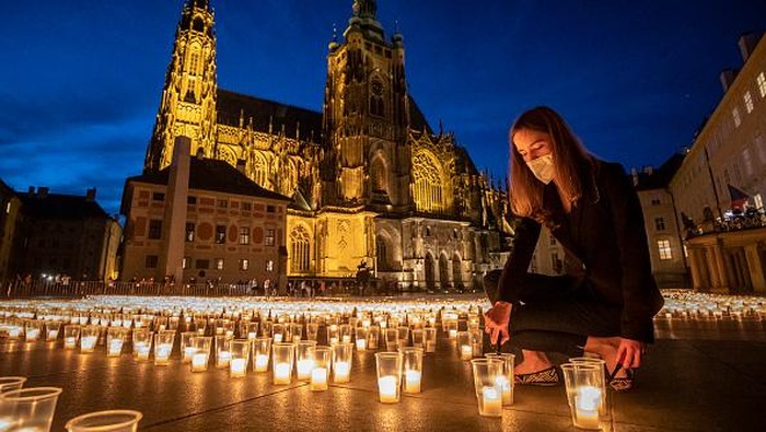 PRAGUE, CZECH REPUBLIC - MAY 10:  A woman lights a candle to commemorate victims of the COVD-19 pandemic at the Prague Castle on May 10, 2021 in Prague, Czech Republic. People commemorated almost 30.000 victims of covid-19 in the country at the Prague Castle during the largest act of reverence in the history of the Prague Castle. The daily numbers of newly confirmed positive COVID-19 cases continue to decline in the Czech Republic. (Photo by Gabriel Kuchta/Getty Images)