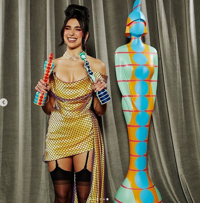 Ia pun memanfaatkan momen karpet merah untuk memamerkan gaya seksinya. Gaun pendek kuning strapless dengan dekorasi ekor panjang menjuntai dari Vivienne Westwood menjadi andalan pelantun Dont Start Now ini. Ia lalu memadukannya dengan choker mutiara bergaya vintage dan stoking seksi bergaya lingerie. (Foto: Instagram/@brits)