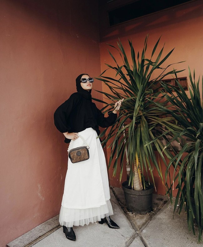 Gaya monokrom juga bisa kamu aplikasikan untuk OOTD hijab Lebaran 2021. Rok bahan lace bisa kamu padukan dengan shirt dan hijab pashmina hitam. Ditambah dengan ankle boots hitam dan sling bag. Foto: Dok. Instagram @anaoctarina.